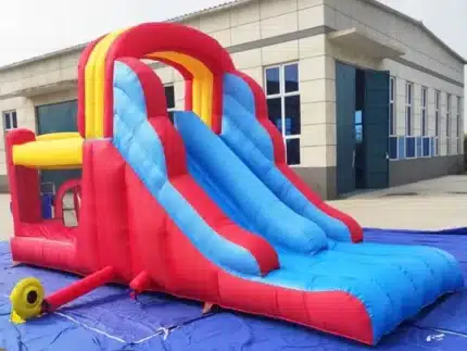 Bright red, yellow, and blue inflatable bouncy castle with dual slides and play area. Perfect for outdoor parties. Buy online in Canada today!