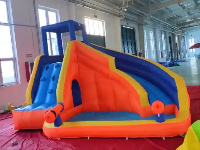 Vibrant inflatable bouncy castle with climbing wall, dual slides, and splash area. Ideal for kids' events. Buy online in Canada at great prices!